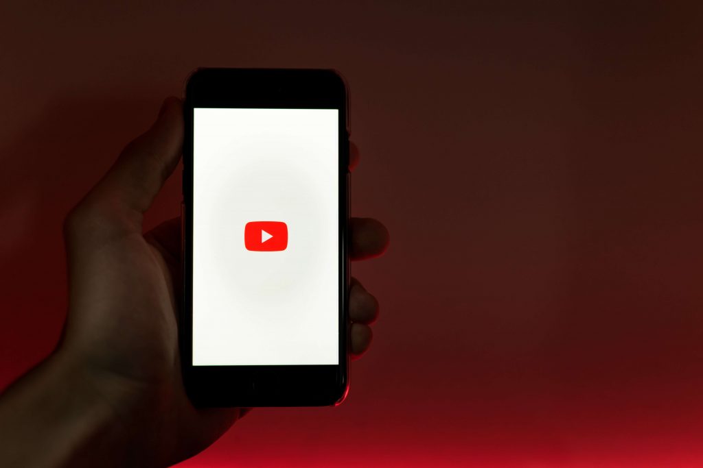 Henkilö pitää kädessään älypuhelinta, jonka näytöllä on Youtube-sovelluksen logo.