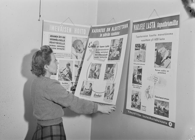 Lasten kasvatukseen liittyviä julisteita Väestöliiton toimiston seinällä vuonna 1948. Niissä lukee "Varjele lasta tapaturmilta", "Kasvatus on aloitettava jo päivän vanhana" ja "Imeväisen hoito".