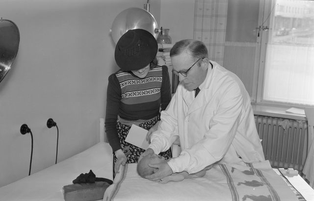 Lääkäri tekee vauvalle terveystarkastusta. Mustavalkoinen vanha valokuva.