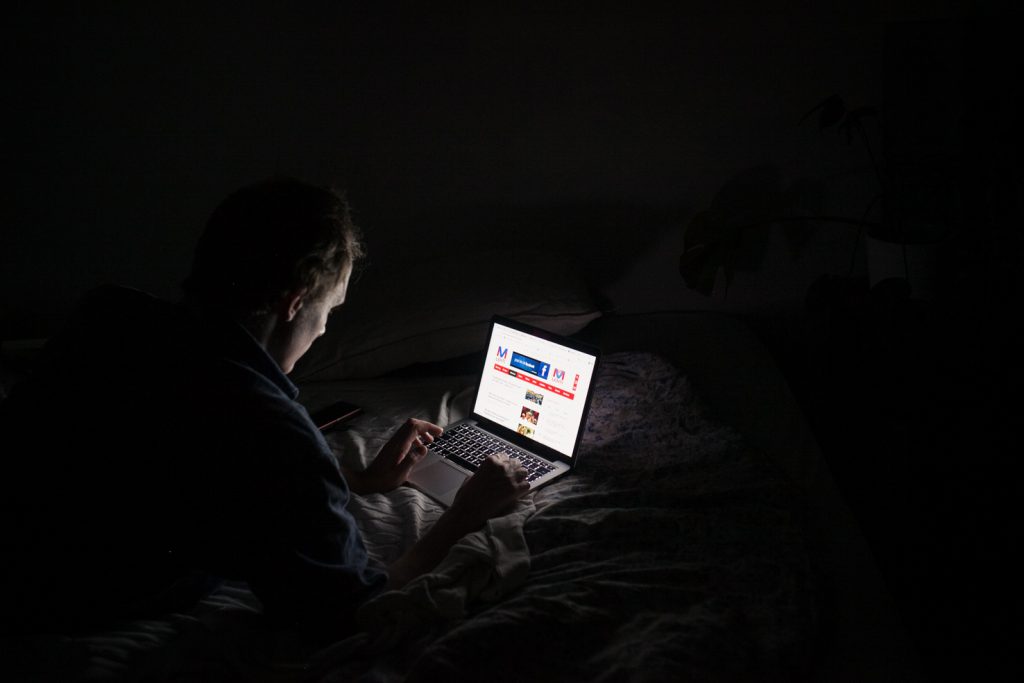 Henkilö lukemassa verkkosivuja pimeässä huoneessa.