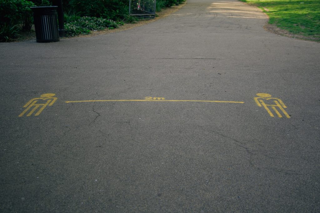 Asfalttiin on vedetty keltaisella maalilla viiva kahden ihmishahmon väliin ja kirjoitettu teksti "2 m".