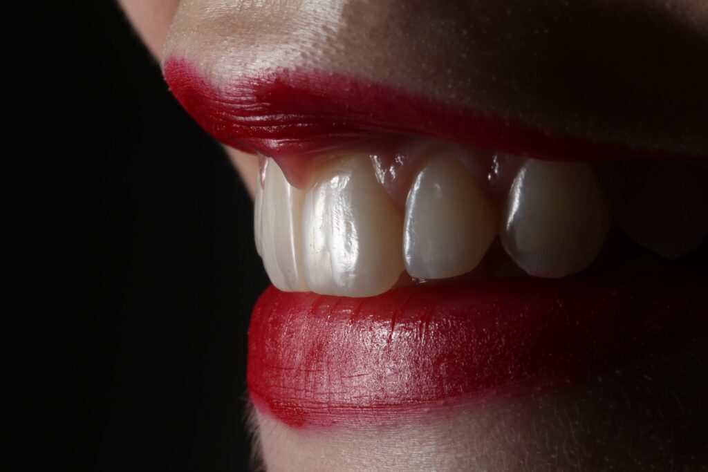 Lähikuva hymyilevän henkilön suusta, jonka huulet on punattu kirkkaanpunaisella.
