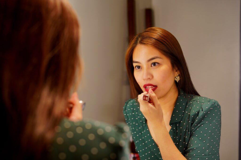 Naishahmo laittaa huulipunaa peilin edessä.