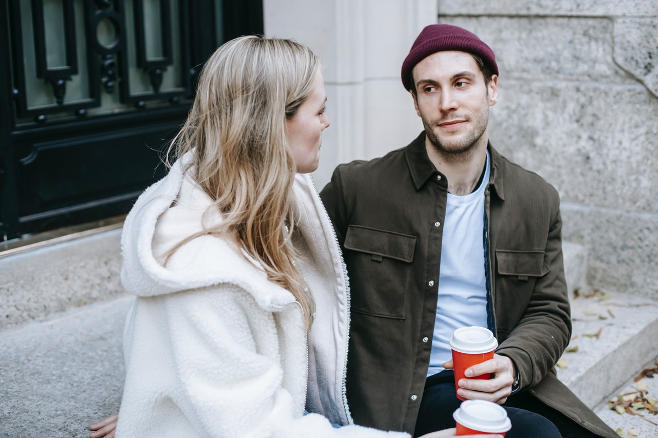 Mies ja nainen istuvat ulkona kahvilla