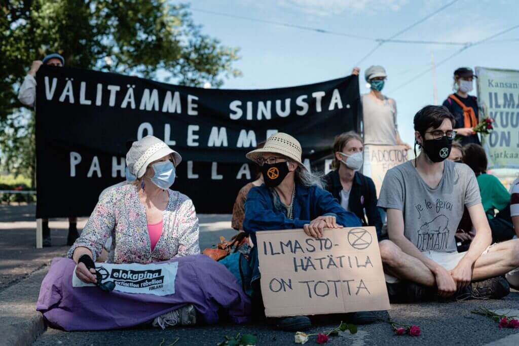 Mielenosoittajia istumassa ajoväylällä Elokapinan mielenosoituksessa.