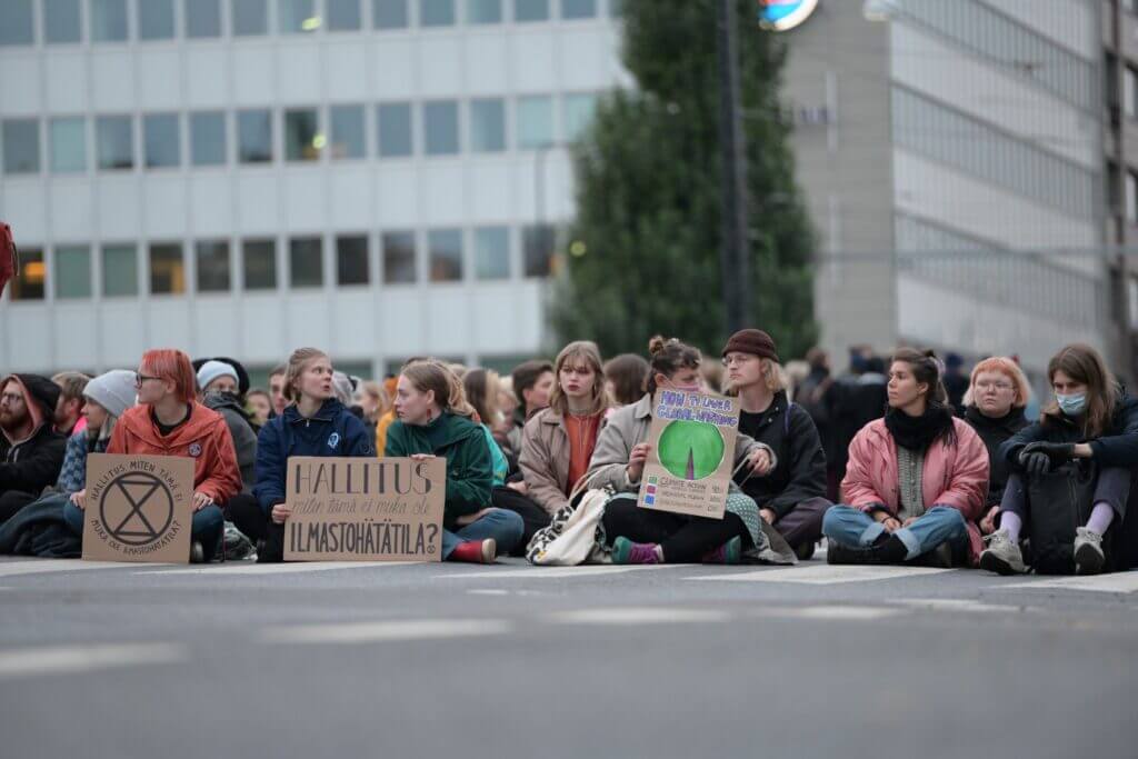 Mielenosoittajia istumassa ajoväylällä Elokapinan mielenosoituksessa. 