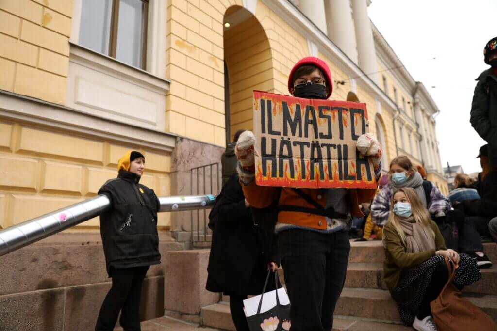 Mielenosoittaja, jonka kyltissä lukee liekkien ympäröimänä teksti "Ilmastohätätila".