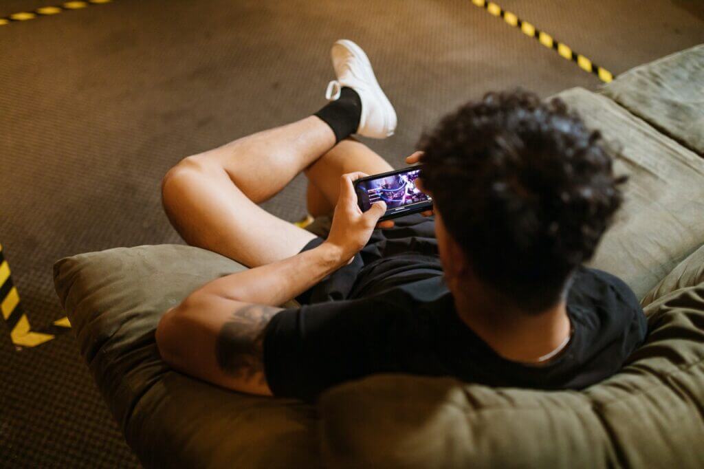 Henkilö katsoo videota älypuhelimelta sohvalla.