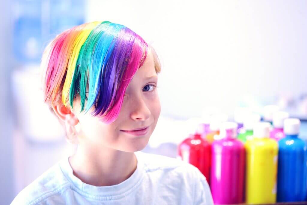 Hymyilevä nuori, jolla on sateenkaaren väreillä värjätyt lyhyet hiukset. 