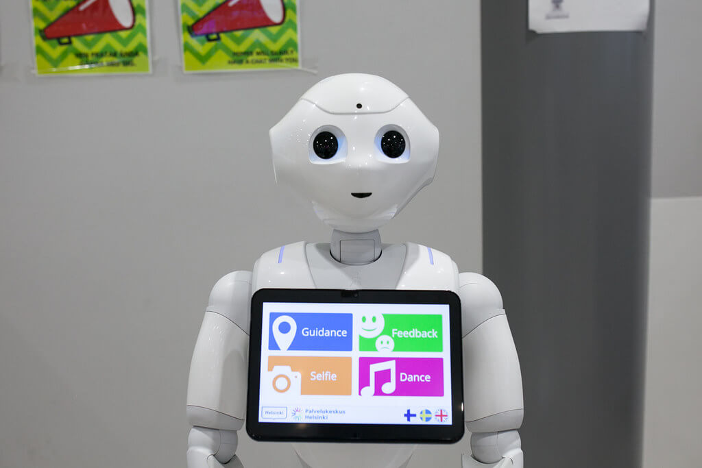Robotti, jossa kiinni olevalla näytöllä lukee englanniksi opastus, palaute, selfie ja tanssi. 
