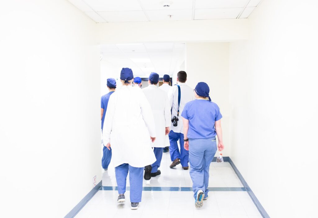 Joukko hoitajia ja lääkäreitä kävelee käytävällä kuvaajasta pois päin. 