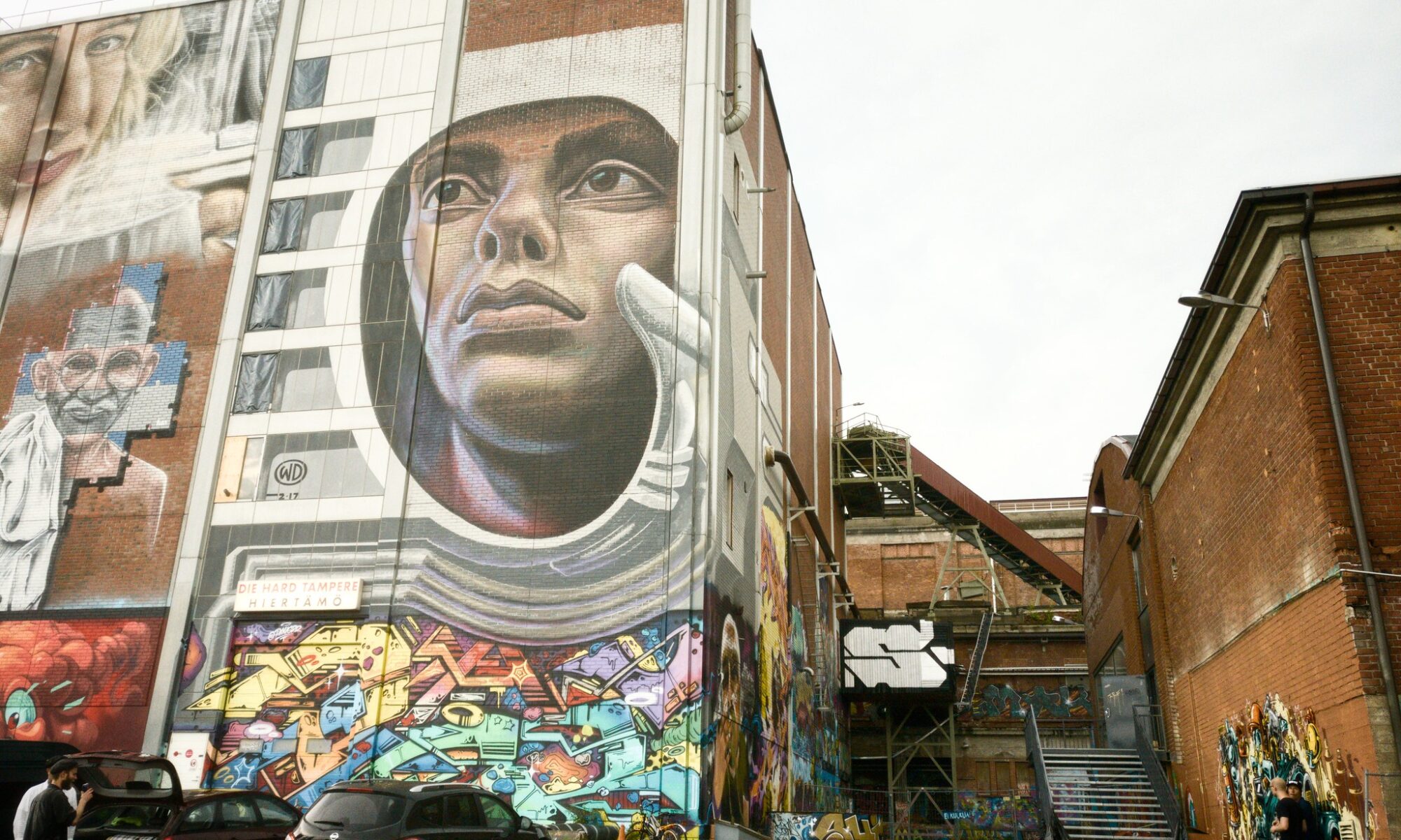 Punatiilisiä tehdasrakennuksia, joihin on maalattu abstrakteja ja esittäviä graffitikuvia.