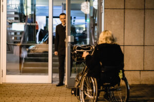 Pyörätuolia käyttävä henkilö on menossa sisään lentoaseman loungeen ja sisäänkäynti on esteetön
