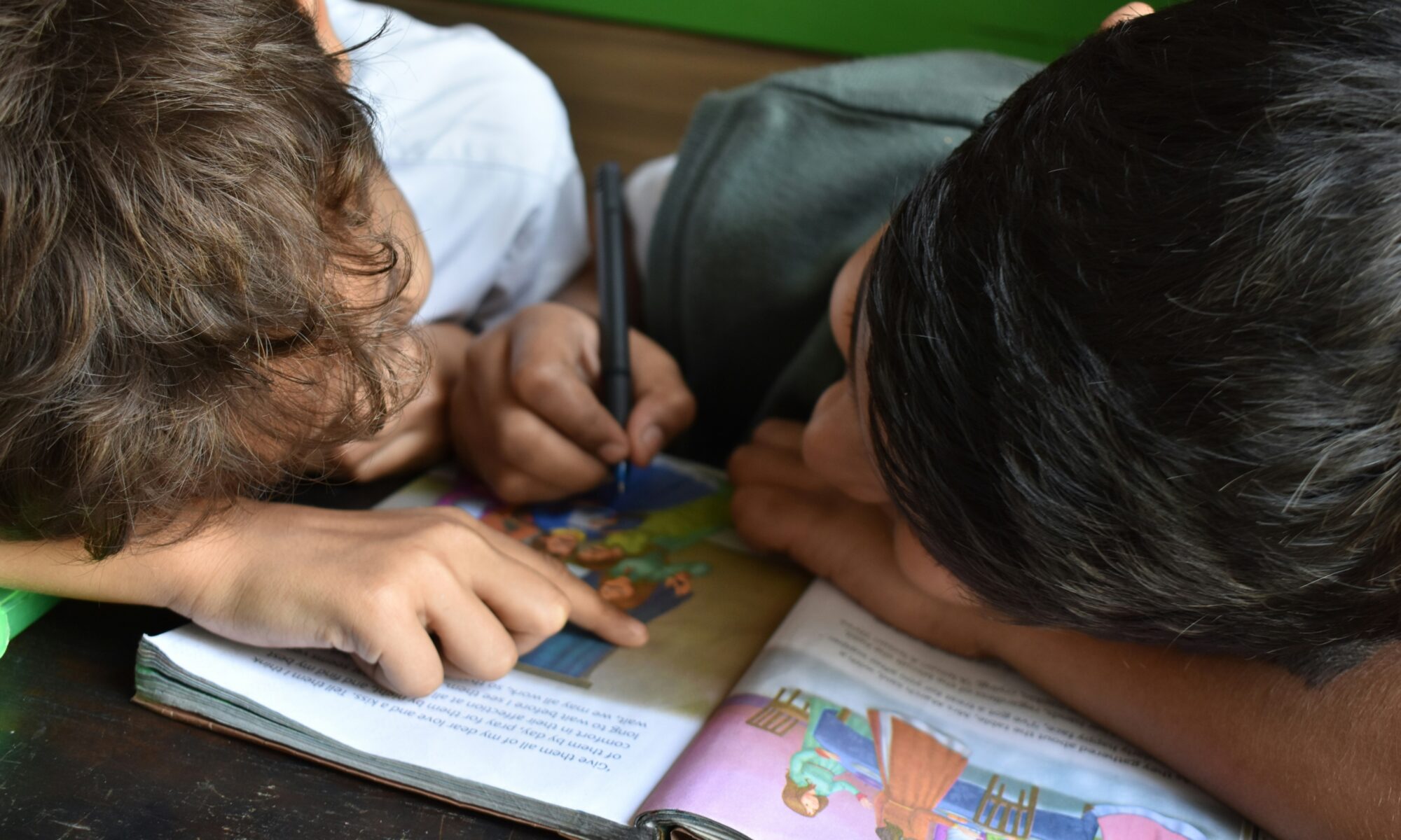 Kaksi lasta lukemassa yhdessä kirjaa.