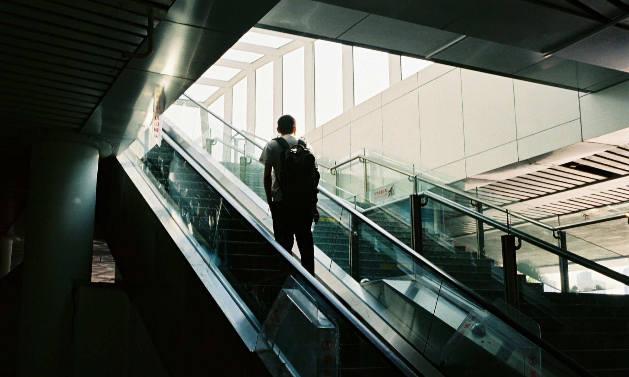 Ihminen matkustaa liukuportaissa ylöspäin muutoin tyhjässä rakennuksessa.
